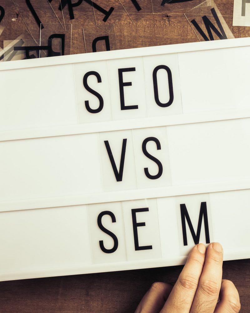 SEO versus SEM, hand insert the letters on the advertising lightbox, concept for SEO and SEM or Search Engine Optimization and Search Engine Matketing